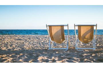 Due sedie sdraio sulla sabbia ed il mare sullo sfondo